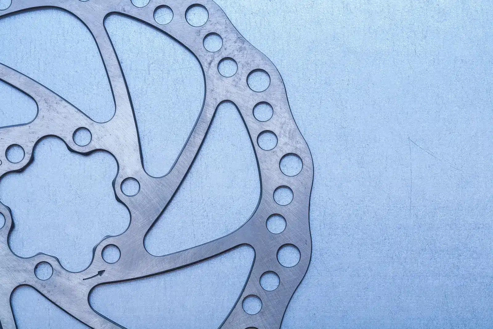 Close-up of a six-bolt bicycle disc brake rotor on a blue workbench