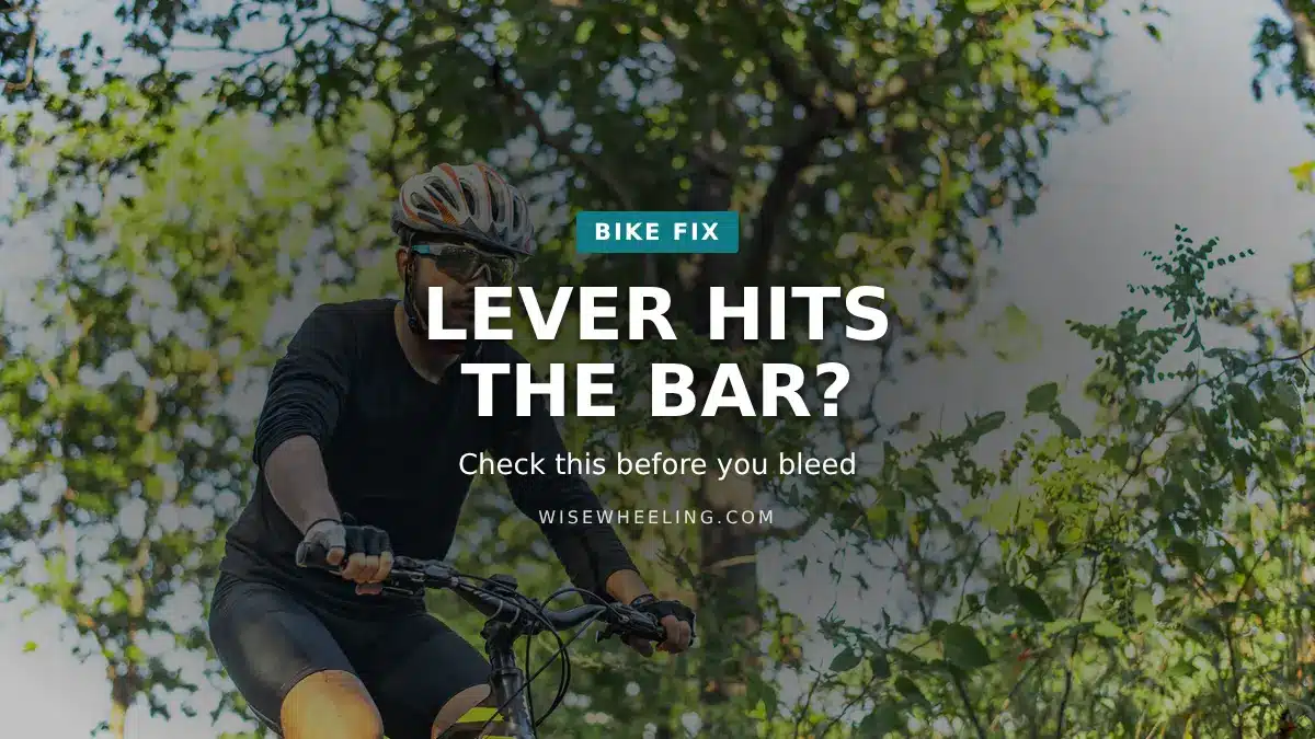 Rider in a black jersey and helmet gripping the brake lever of a mountain bike on a wooded trail