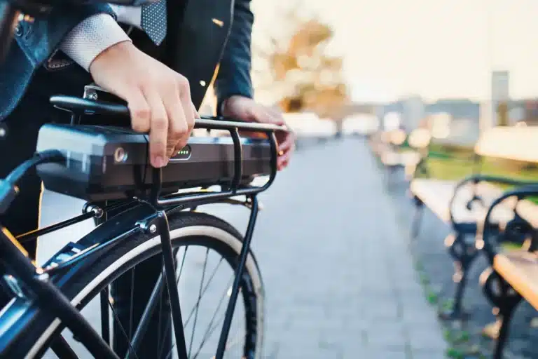 Rider fitting a battery onto the rear rack of an electric bicycle