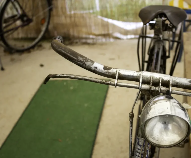 Old bicycle handlebar with worn, flaking paint exposing bare metal
