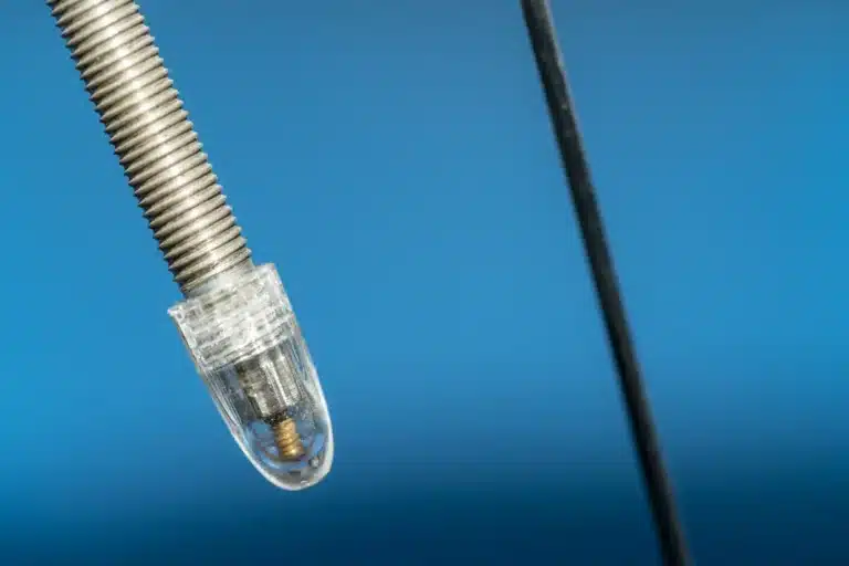 Close-up of a threaded Presta valve stem with a clear plastic cap on the tip